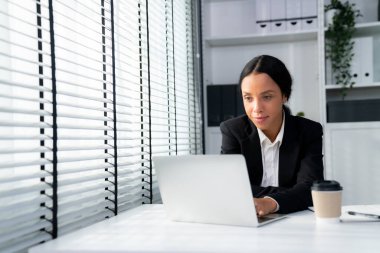 This photo depicts a young African American and competent woman at her workplace. A female employee in her office at work.