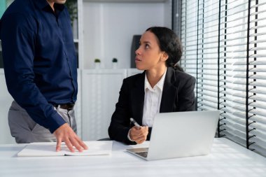 Competent female employee discussing with her colleague, employer using laptop at her office. Interpersonal relations among coworkers.