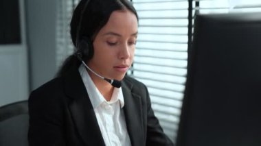 Competent african american female operator working on computer and while talking with clients. Concept relevant to both call centers and customer service offices.