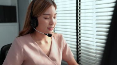Competent female operator working on computer and while talking with clients. Concept relevant to both call centers and customer service offices.
