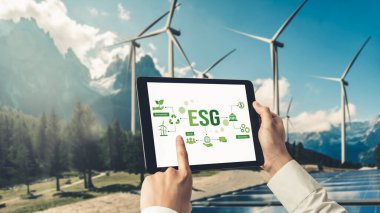 Çevre tasarrufu ve ESG iş konsepti için yeşil iş dönüşümü. İşadamı, çevre dostu yönetime ve alternatif temiz enerji kullanımına yönelik kurumsal bir hedef belirlemek için tablet kullanıyor.