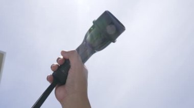 Yakın plan, çevresel kaygılar için alternatif sürdürülebilir temiz ve yeşil enerji kavramı olarak arka planda gün ortası gökyüzü ile elektrikli araç için bir EV kapsülü kavrıyor.