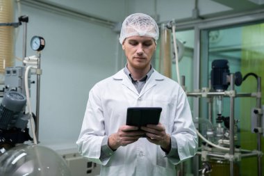 Erkek bilim adamı, kenevir yaprağı ve kenevir bitkilerinden elde edilen kimya verilerini taşıyan bir tablet taşırken esrar çıkarma laboratuvarında çalışan eczacı. Tıbbi esrar özütü