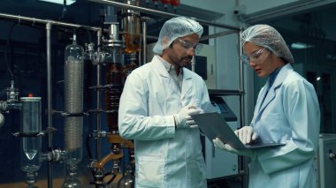 Kimyasal ve biyomedikal deney laboratuarında çalışan profesyonel üniformalı iki bilim adamı.