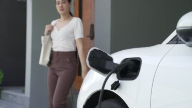 Bir kadın evinde elektrikli araç şarj aletinin fişini çekiyor. İlerici bir yaşam tarzında elektrikli araçların kullanımı, temiz ve sağlıklı bir çevreye katkıda bulunur..