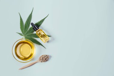Şişede CBD yağı, damlacık kapağı, sativa yeşil kenevir ve kenevir tohumu bulunan yasallaştırılmış marihuana özellikleri. Copyspace ve reklam için esrar ürünü.