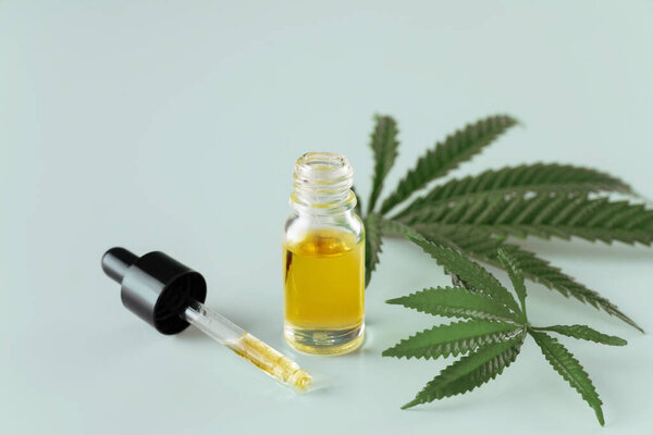 Лист конопли конопли конопли конопли с контейнером масла CBD с крышкой капельницы на белом фоне. Легализованная марихуана.