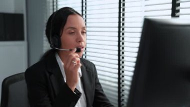 Competent african american female operator working on computer and while talking with clients. Concept relevant to both call centers and customer service offices.