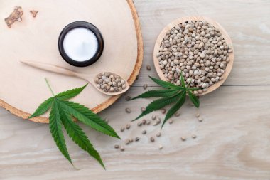Kenevir ve kozmetik konseptinde CBD yağ şişeleri, krema kavanozu ve kenevir tohumları bulunur. Cilt ürünleri için yasallaştırılmış esrar.