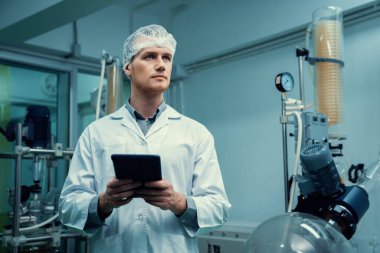 Erkek bilim adamı, esrar çıkarma laboratuarında çalışan eczacı kenevir yaprağı ve kenevir bitkilerinden alınan kimya bilgilerini içeren tablet taşıyor. Tıbbi esrar özütü.