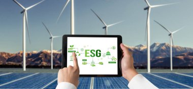 Çevre tasarrufu ve ESG iş konsepti için yeşil iş dönüşümü. İşadamı, çevre dostu yönetime ve alternatif temiz enerji kullanımına yönelik kurumsal bir hedef belirlemek için tablet kullanıyor.