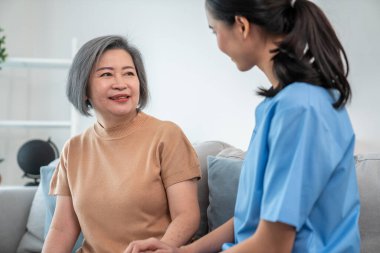 A contented senior woman visited by her personal caregiver and hold each others hands.
