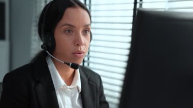 Competent african american female operator working on computer and while talking with clients. Concept relevant to both call centers and customer service offices.