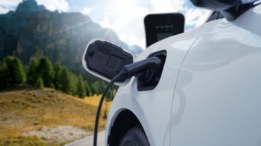 Elektro jeneratör sürücüsüyle enerji sürdürülebilir araba gücü, şarj istasyonunda şarj edilen batarya, ilerici seyahat konsepti için dağ zeminine sahip. Temiz ortamın sembolü olarak doğadaki EV otomobil.