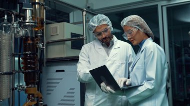 Kimyasal ve biyomedikal deney laboratuarında çalışan profesyonel üniformalı iki bilim adamı.