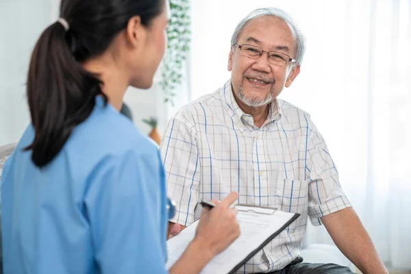 Young Female Doctor Inquires Personal Information Contented Senior Home Medical — Stock fotografie