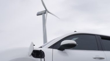 Çevreyi korumak için rüzgar türbininden yeşil ve yenilenebilir enerjiyle çalışan şarj istasyonunda şarj edilen gelişmiş gelecek enerji altyapısı konsepti.