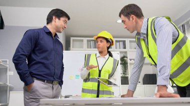 Engineers and competent employer discussing plans and blueprints together with tablet in the office. Concept of team contribution of ideas for engineering project.