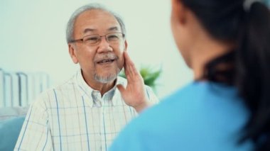 A young female doctor inquires about personal information of a contented senior at home. Medical care for the elderly, elderly illness, and nursing homes, home care.