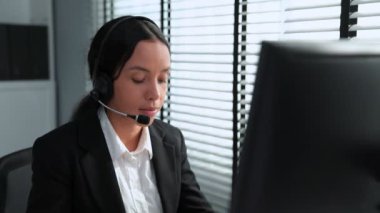 Competent african american female operator working on computer and while talking with clients. Concept relevant to both call centers and customer service offices.
