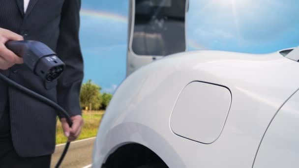 进步的商人在他的山路上用充电站给电动车充电 电动车是由可再生能源驱动的 用于清洁环境 电动车的能源可持续性概念 — 图库视频影像