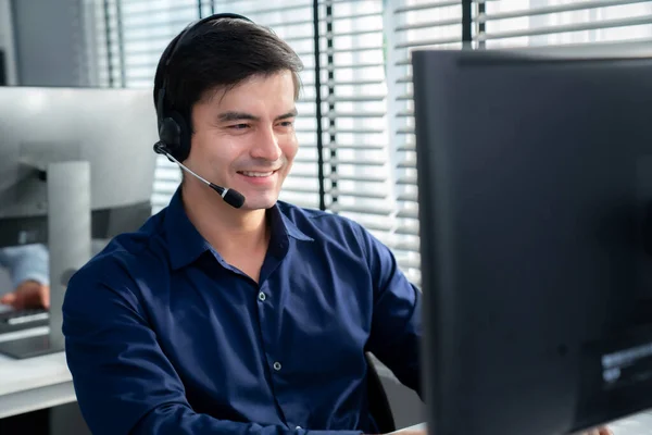 Young competent asian male call center agent working at his computer while simultaneously speaking with customers. Concept of an operator, customer service agent working in the office with headset.