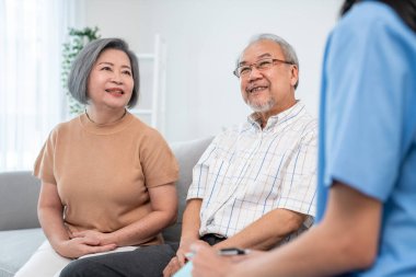 Female doctor visiting a contented elderly couple at their home. Health care, senior health support staff.