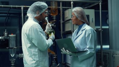 Kimyasal ve biyomedikal deney laboratuarında çalışan profesyonel üniformalı iki bilim adamı.