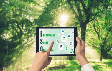 Çevre tasarrufu ve ESG iş konsepti için yeşil iş dönüşümü. İşadamı, çevre dostu yönetime ve alternatif temiz enerji kullanımına yönelik kurumsal bir hedef belirlemek için tablet kullanıyor.