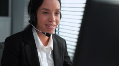 Competent african american female operator working on computer and while talking with clients. Concept relevant to both call centers and customer service offices.