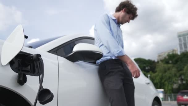 Geschäftsmann Anzug Mit Progressivem Ehrgeiz Stützt Sich Auf Sein Elektrofahrzeug — Stockvideo