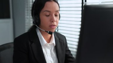 Competent african american female operator working on computer and while talking with clients. Concept relevant to both call centers and customer service offices.