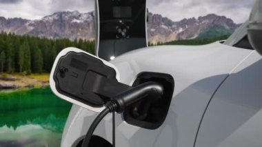Temiz çevre için temiz enerjinin yol açtığı ilerici elektrikli araba kavramının arka planı olarak dağın tepesinde bulutun zaman kavramının yer aldığı doğal manzara. EV araba şarj istasyonunda şarj oluyor..