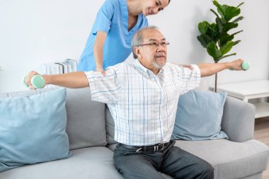 Contented senior patient doing physical therapy with the help of his caregiver. Senior physical therapy, physiotherapy treatment, nursing home for the elderly