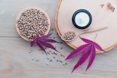 Kenevir ve kozmetik konseptinde CBD yağ şişeleri, krema kavanozu ve kenevir tohumları bulunur. Cilt ürünleri için yasallaştırılmış esrar.