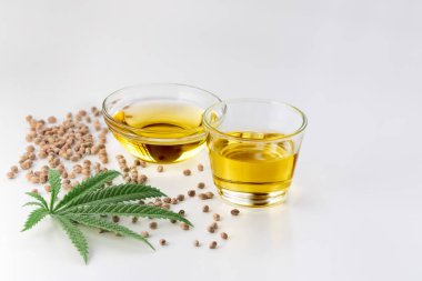 CBD yağı, cam kasede THC tintürü, damlalık kapaklı şişe ve boş arka planda kenevir yaprağı minimalizmle çevrili bir yığın kuru kenevir tohumu. Yasal marihuana konsepti.