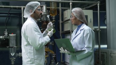 Kimyasal ve biyomedikal deney laboratuarında çalışan profesyonel üniformalı iki bilim adamı.