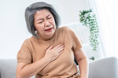 An agonizing elderly woman is experiencing chest pain. Medical attention, senior care service.